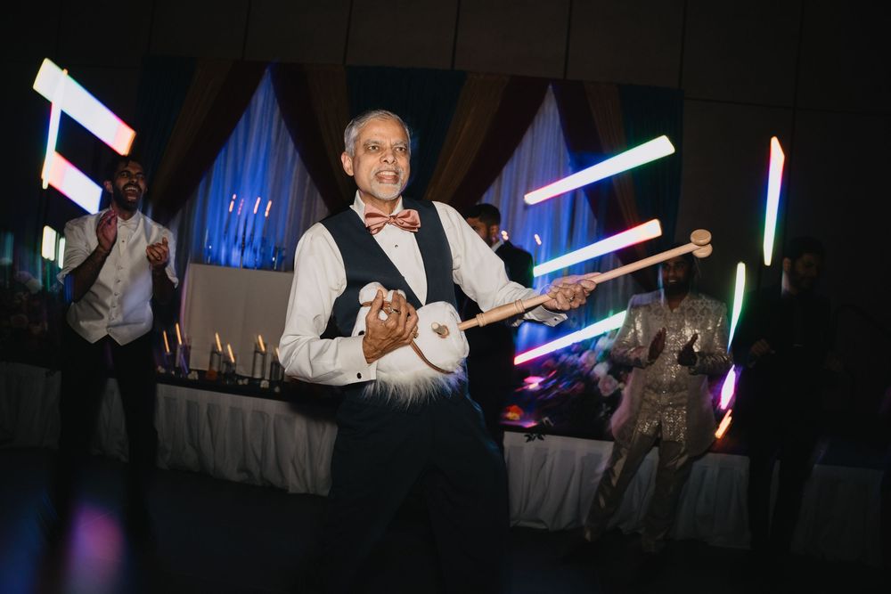 An older gentleman plays a string instrument with glowing light sticks during a festive wedding reception.at Sandia Resort and Casino