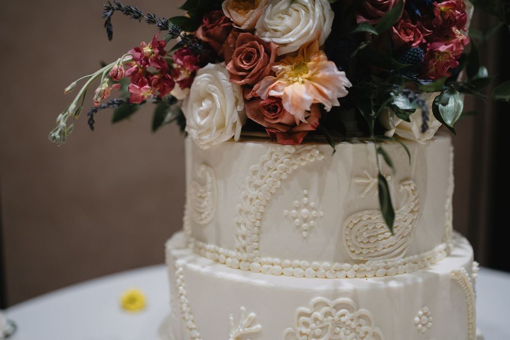 Three-tier white wedding cake with paisley detailing topped with colorful fresh flowers.at Sandia Resort and Casino