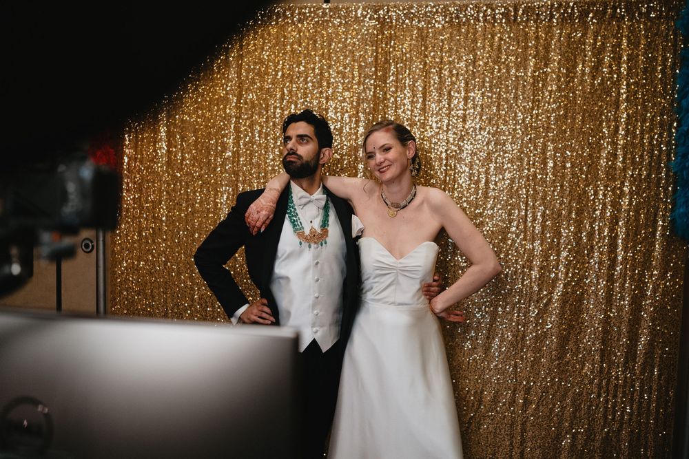 Bride and groom posing together in front of a glittering gold sequin backdrop at their wedding reception.at Sandia Resort and Casino