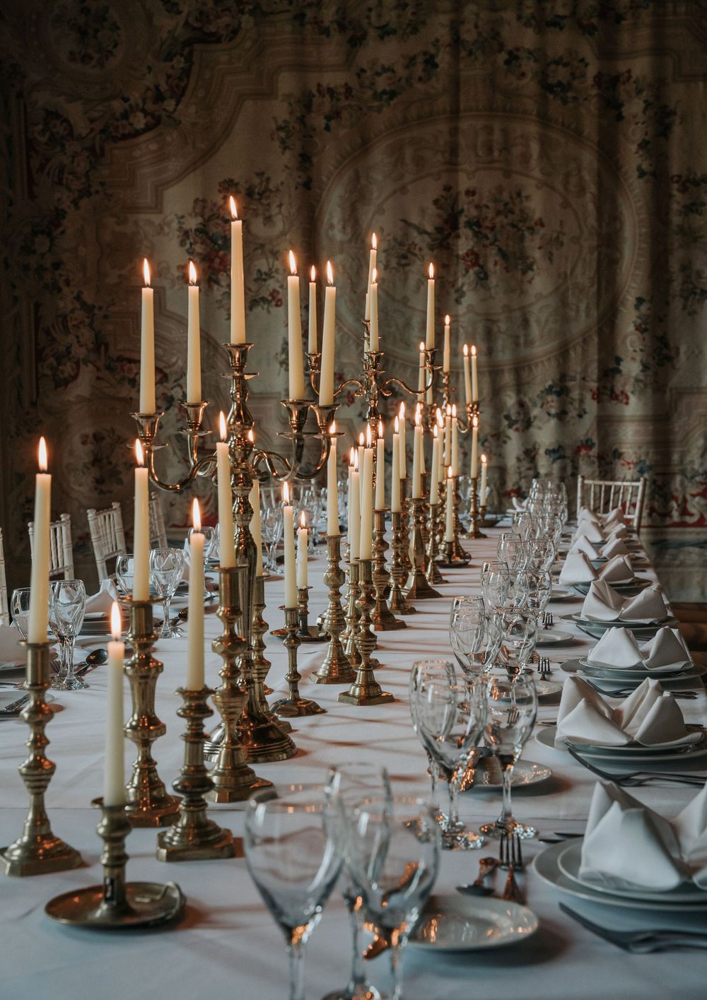Elegant wedding reception table styling with brass candlesticks and white linen at Huntsham Court