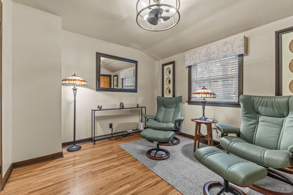 Comfortable sitting room with green leather recliner chairs, hardwood floors, and Tiffany-style floor lamp.