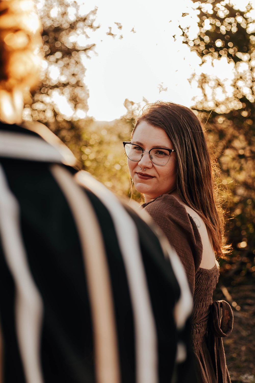 A series of artistic portraits shot through black railings at golden hour with warm sunset lighting and bokeh effects.