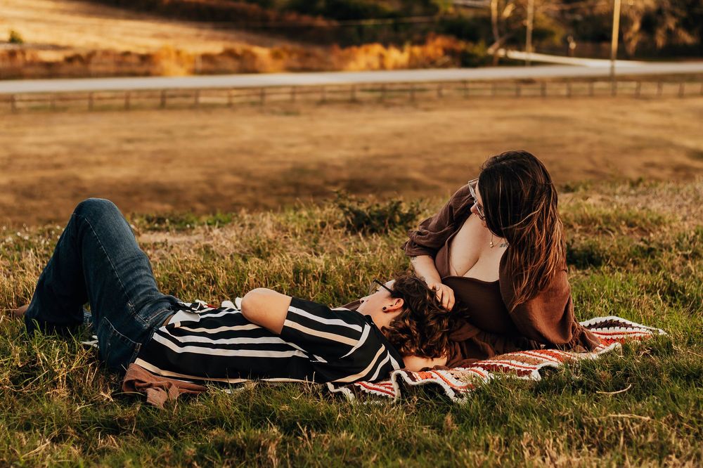 People relaxing on a grassy hillside during golden hour at sunset.