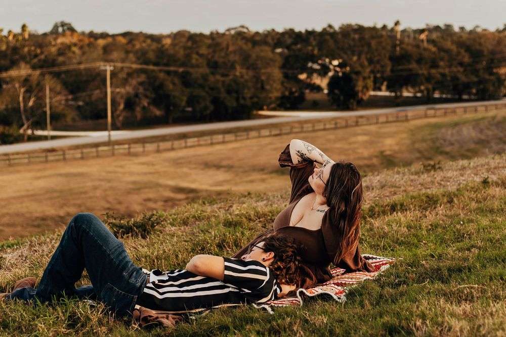 People lounging on a grassy slope with warm sunlight casting long shadows across the landscape.