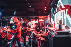 Rock band performing on stage with dramatic red lighting and video screens. live event photography st louis