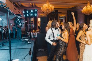 Wedding reception band performing under crystal chandeliers while guests dance on the dance floor. live event photography st louis