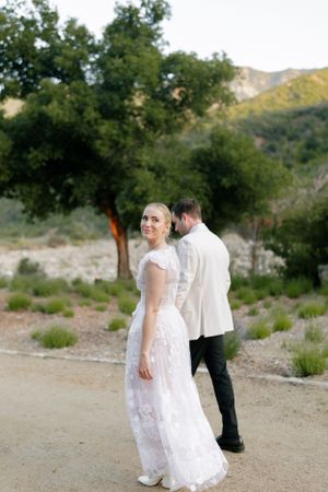Couple in formal wedding attire posing on mountain trail.