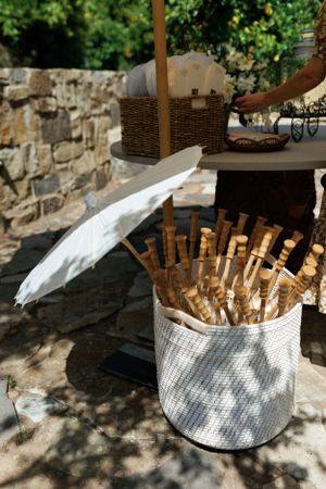 White basket filled with paper parasols at outdoor wedding venue.