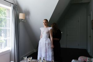 An elegant white lace wedding dress photographed in a bright, minimalist room setting.