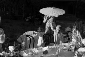 Black and white photo of dinner party guests with decorative paper parasols.