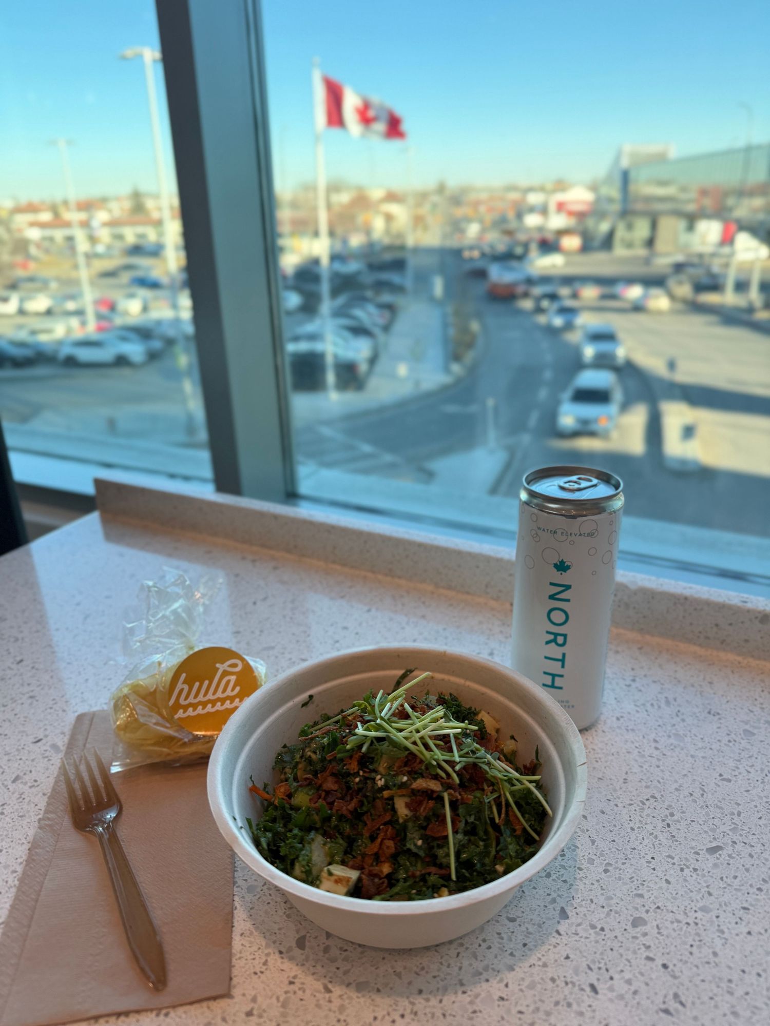 Three plates of fresh salad served at a restaurant with a Canadian flag visible through the window.