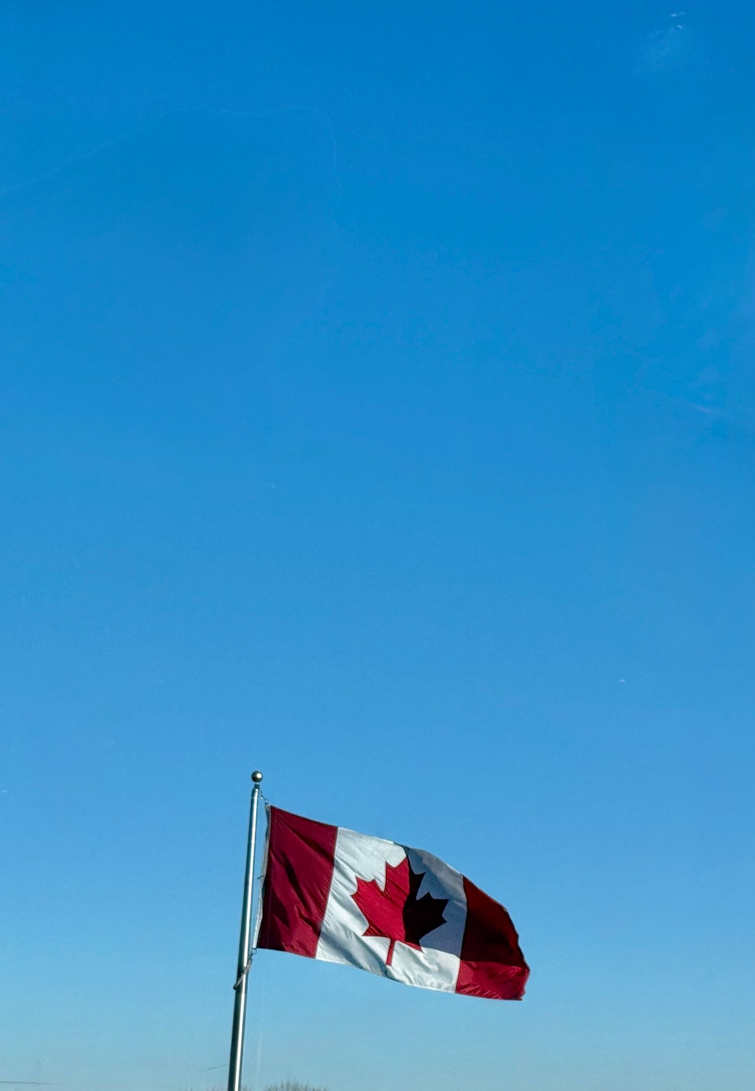 Canadian flag flying against bright blue sky in sequence showing flag waving in the wind.
