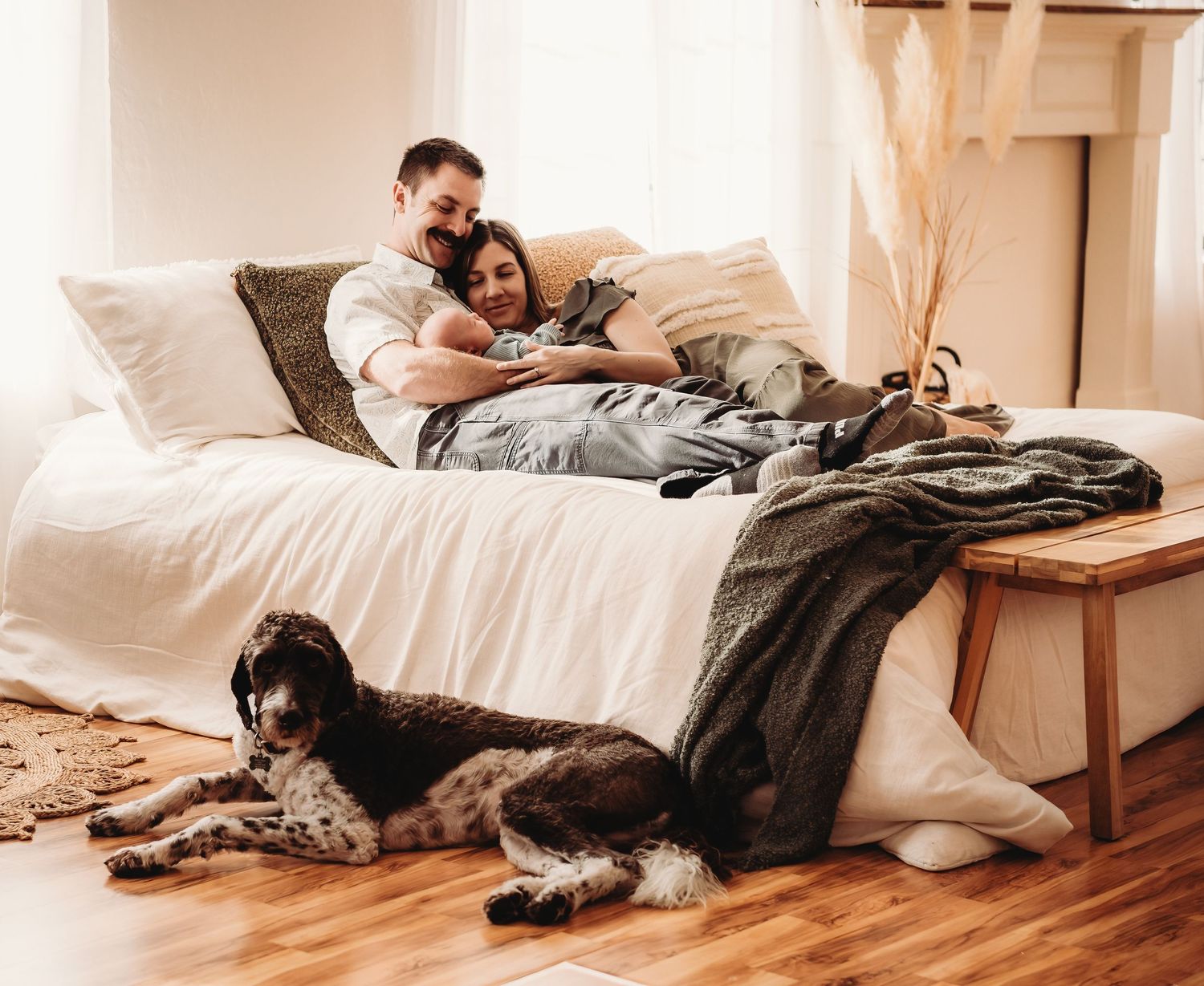 Cozy scene of couple relaxing on bed with dog while looking at device together.