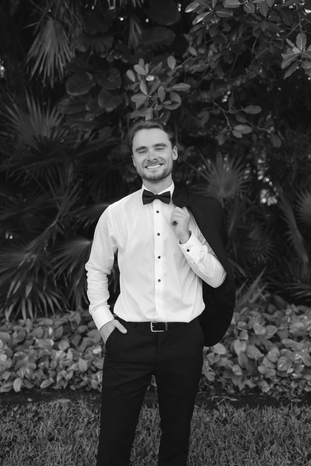 Black and white portraits of groomsman in formal attire against foliage background.
