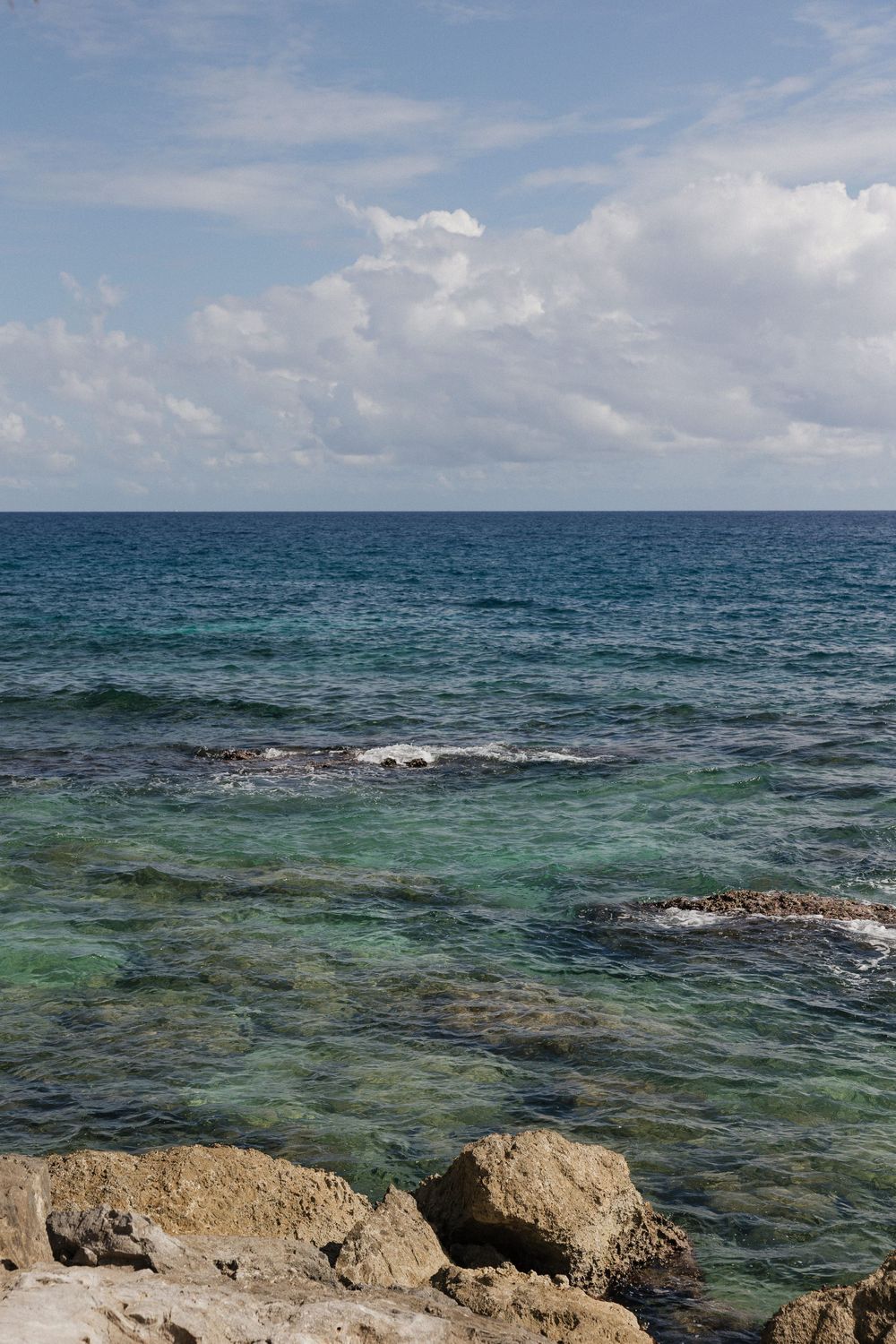 Tropical seascape with turquoise waters and rocky coastline under blue sky.