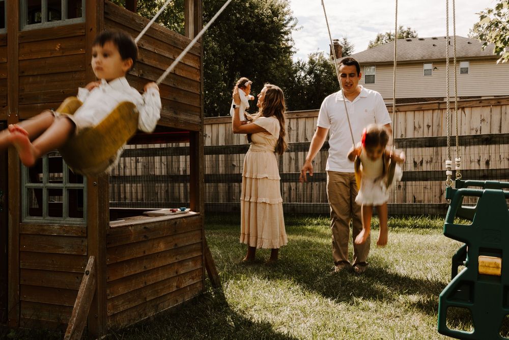 Family enjoying a warm afternoon in the backyard with a wooden playset and swing in vintage-toned photography.