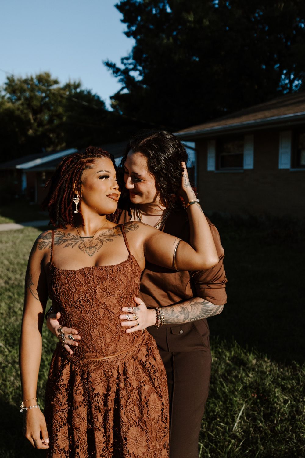 Two people in brown outfits share intimate moments during an outdoor sunset photoshoot.