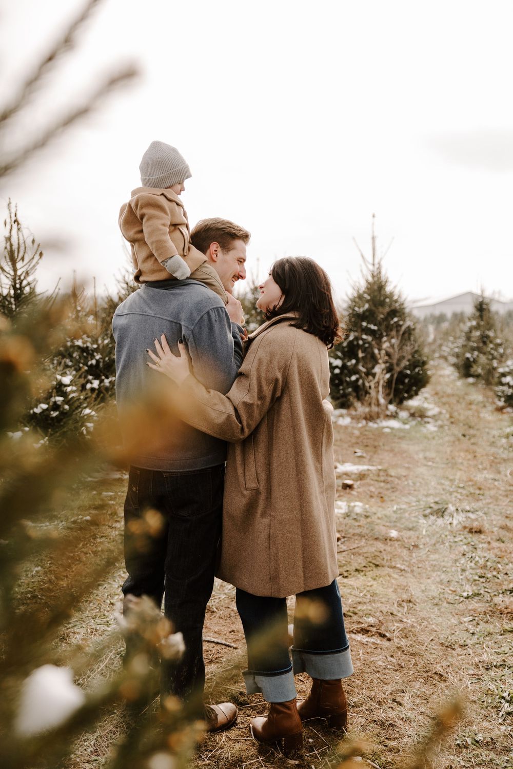 Couple walking together through a winter Christmas tree farm on a snowy afternoon.