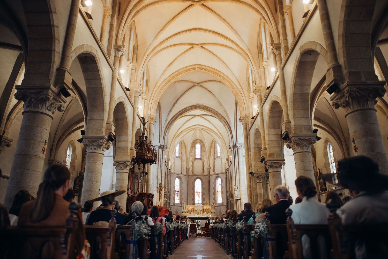Wide interior view of elegant stone church filled with wedding guests during a romantic ceremony.