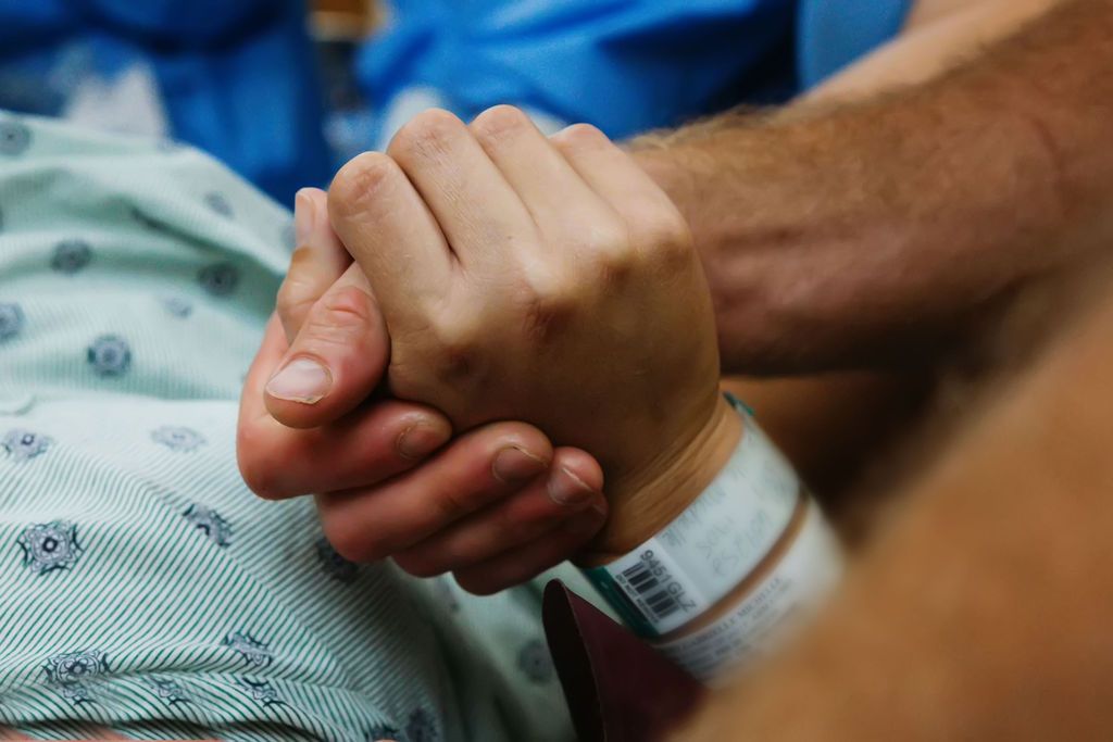 A comforting hand holding a hospital patient's hand, showing care and support during medical treatment.