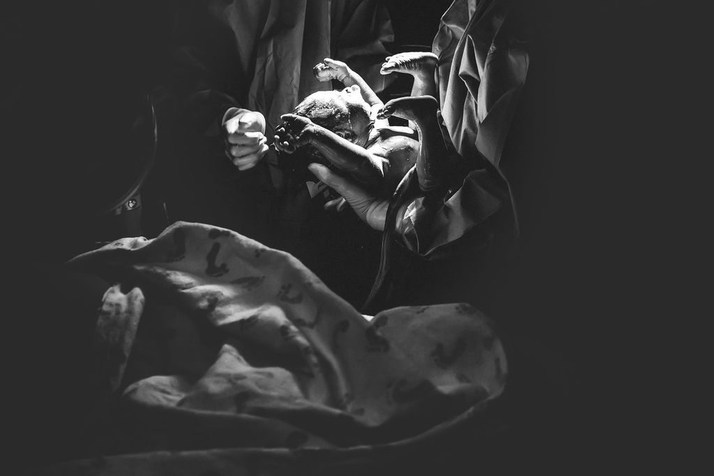 Black and white photo of hands holding a vintage camera, draped fabric in background.