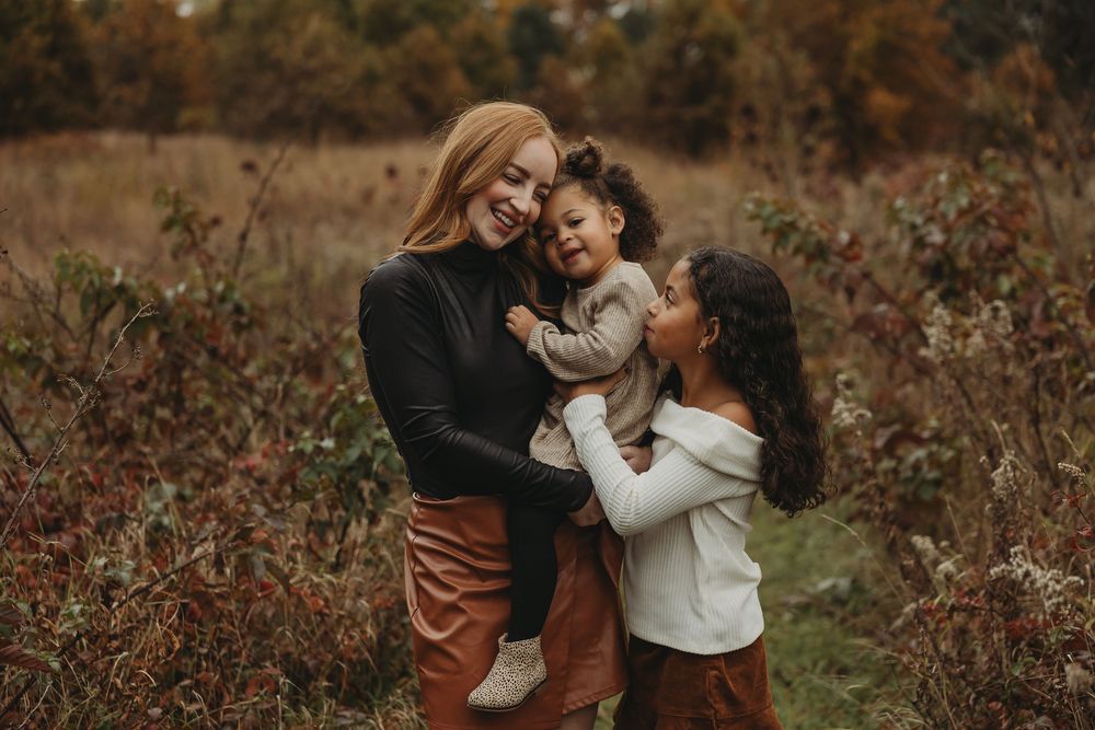 A couple embraces in a field of autumn foliage during a romantic outdoor photo session.