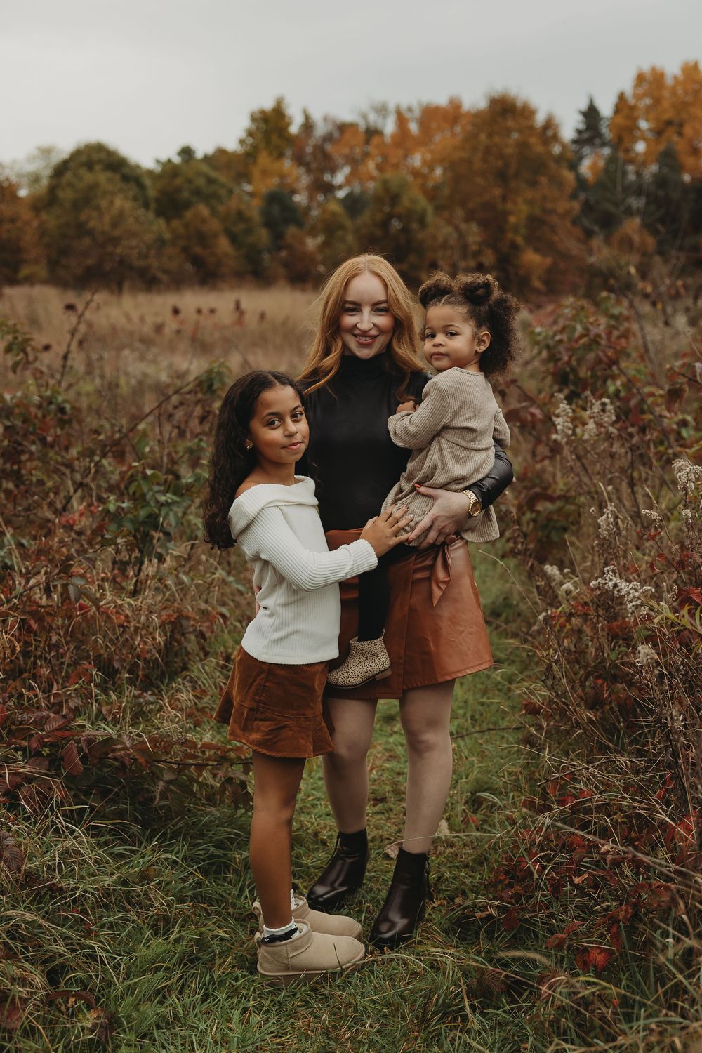 A group enjoys a playful moment together in a rustic autumn field with tall grass and warm fall colors.