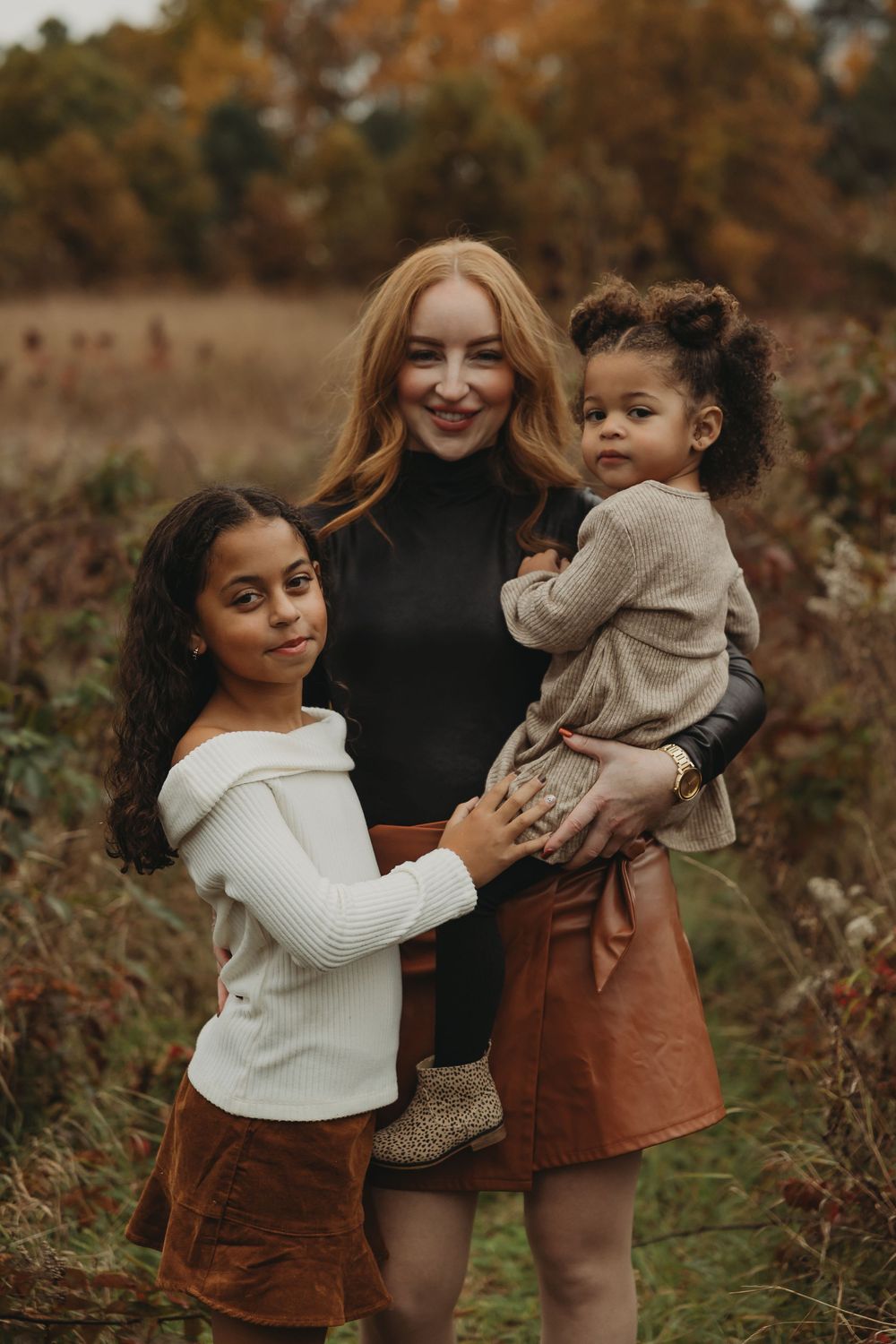 A candid autumn photoshoot in nature showing joyful moments between people wearing cozy sweaters and brown skirts.