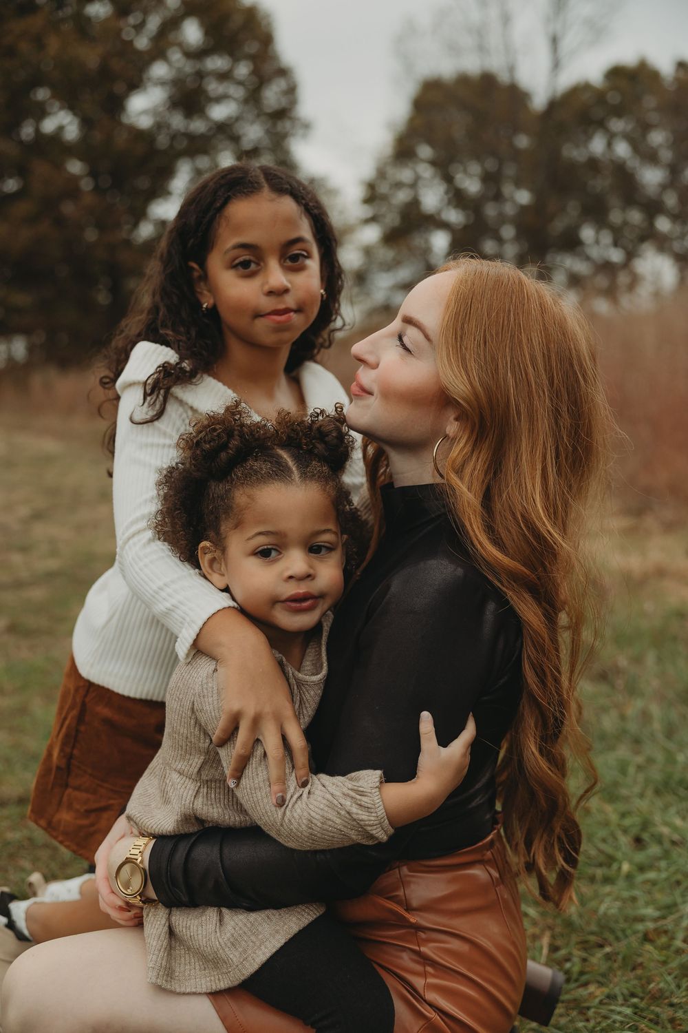A loving embrace shared between a parent and child in a grassy autumn field during a candid outdoor photoshoot.