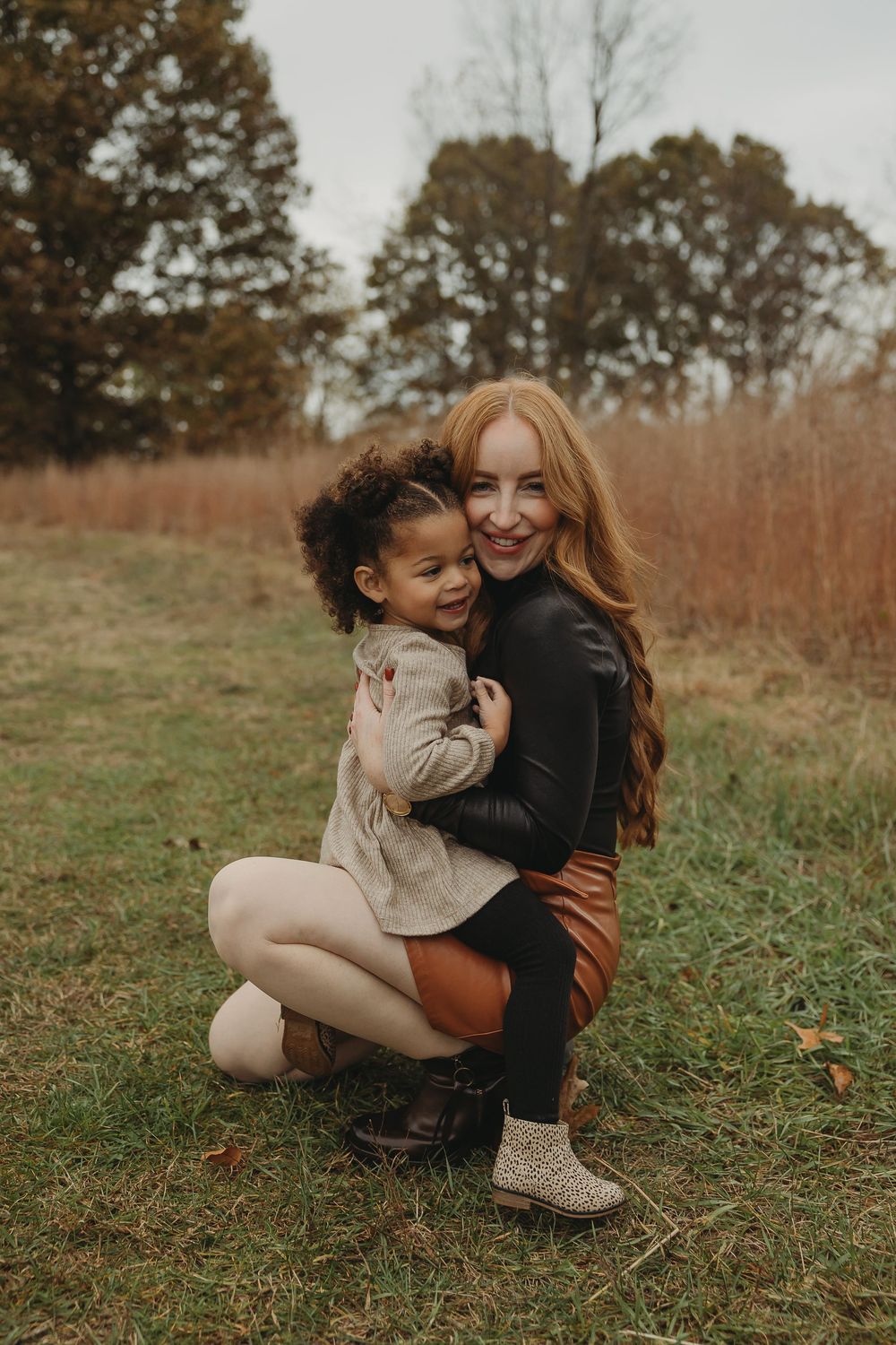 A heartwarming embrace between two people sitting in a grassy autumn field during golden hour.