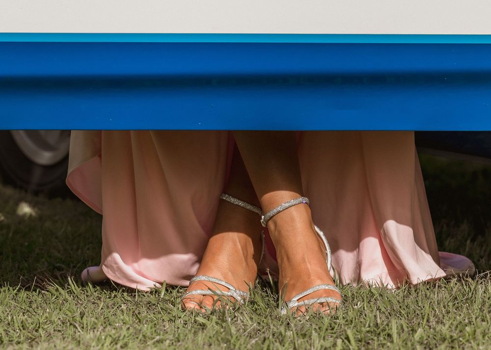 Formal/Graduation photography session young woman's feet in silver strappy heeled sandals wearing a pink gown, posing for photos.