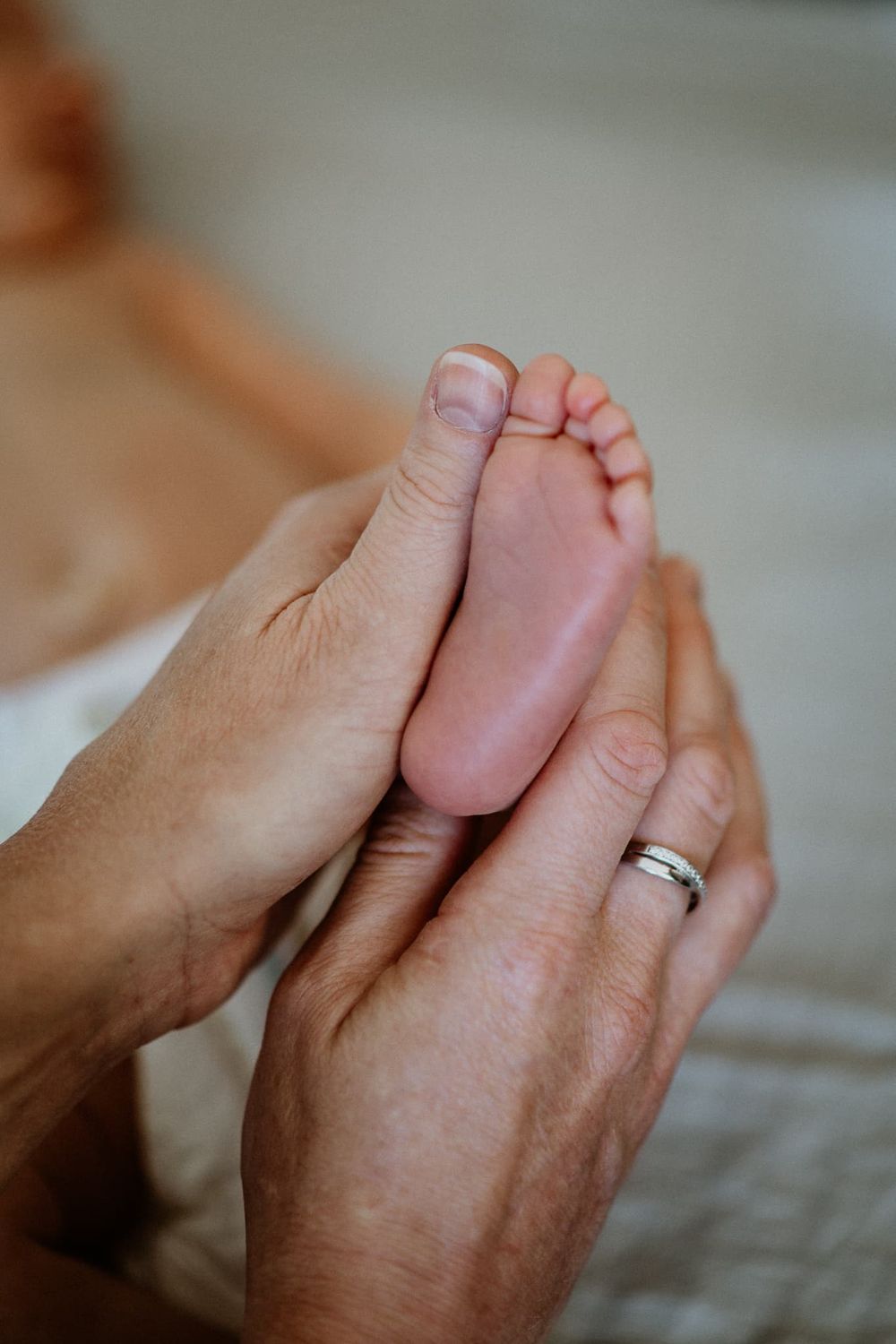 Mamma håller i sin nyfödda bebis fot, och den lilla foten är lika lång som hennes tumme.