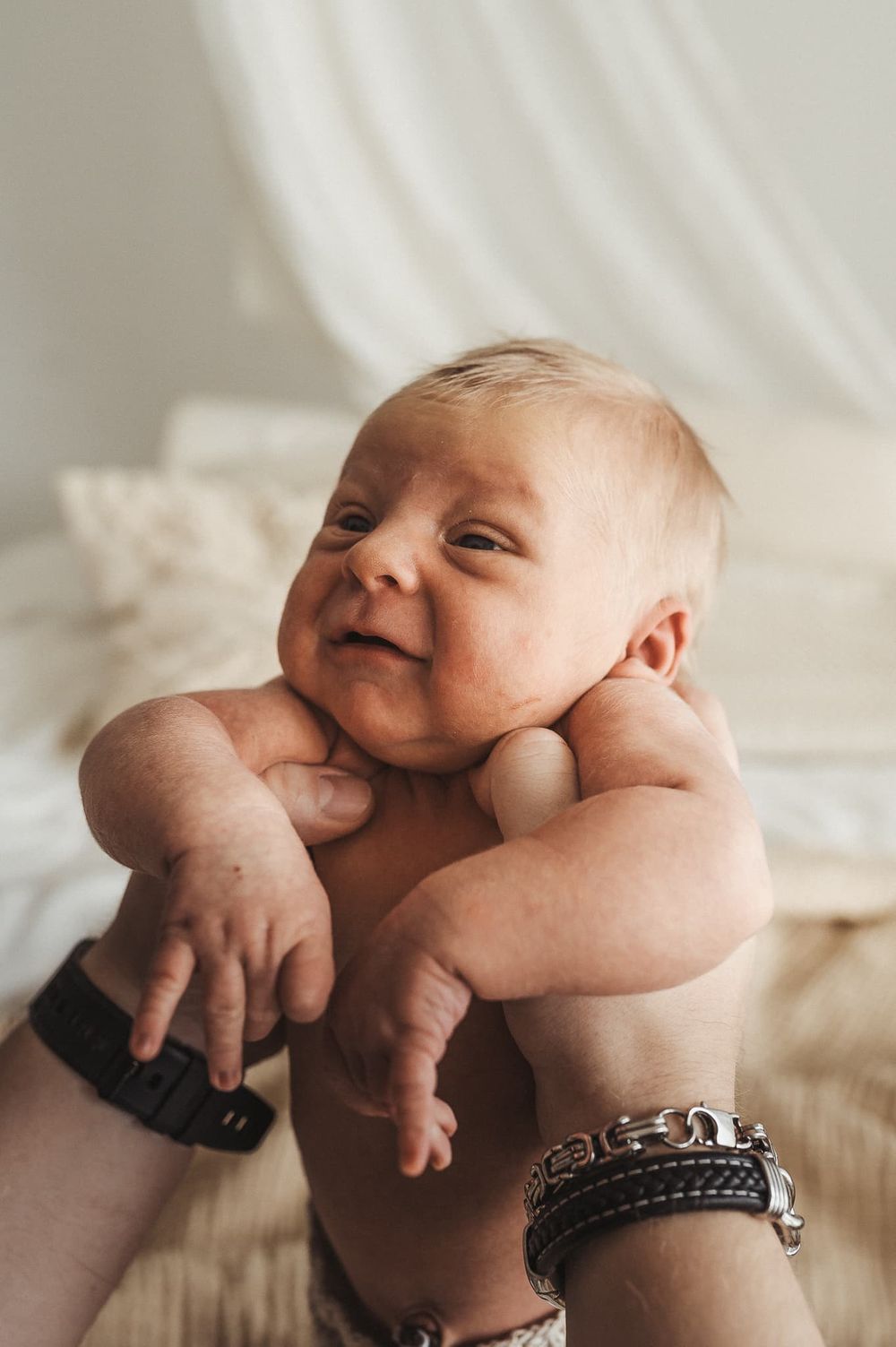 Pappa håller upp sin nyfödda bebis i Fotograf Veronica Engs studio i Mullsjö / Jönköping. Pappan har klocka och armband.