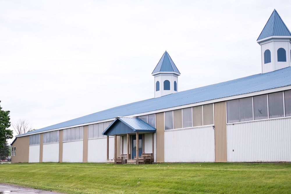 Long white equestrian facility building with blue roof and multiple cupolas.