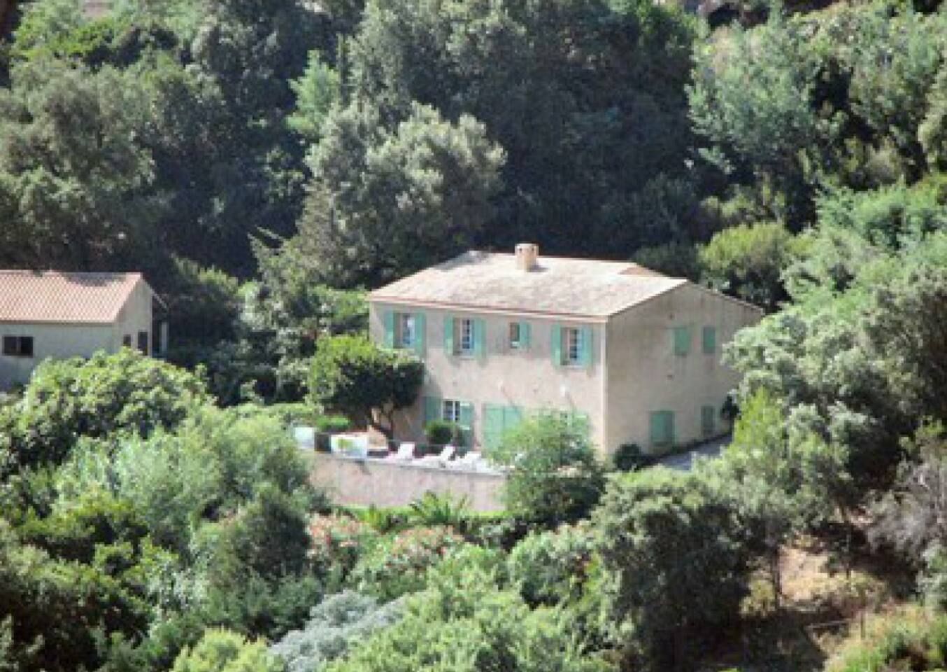 Panoramic view of Mediterranean houses nestled among lush green trees on a hillside.