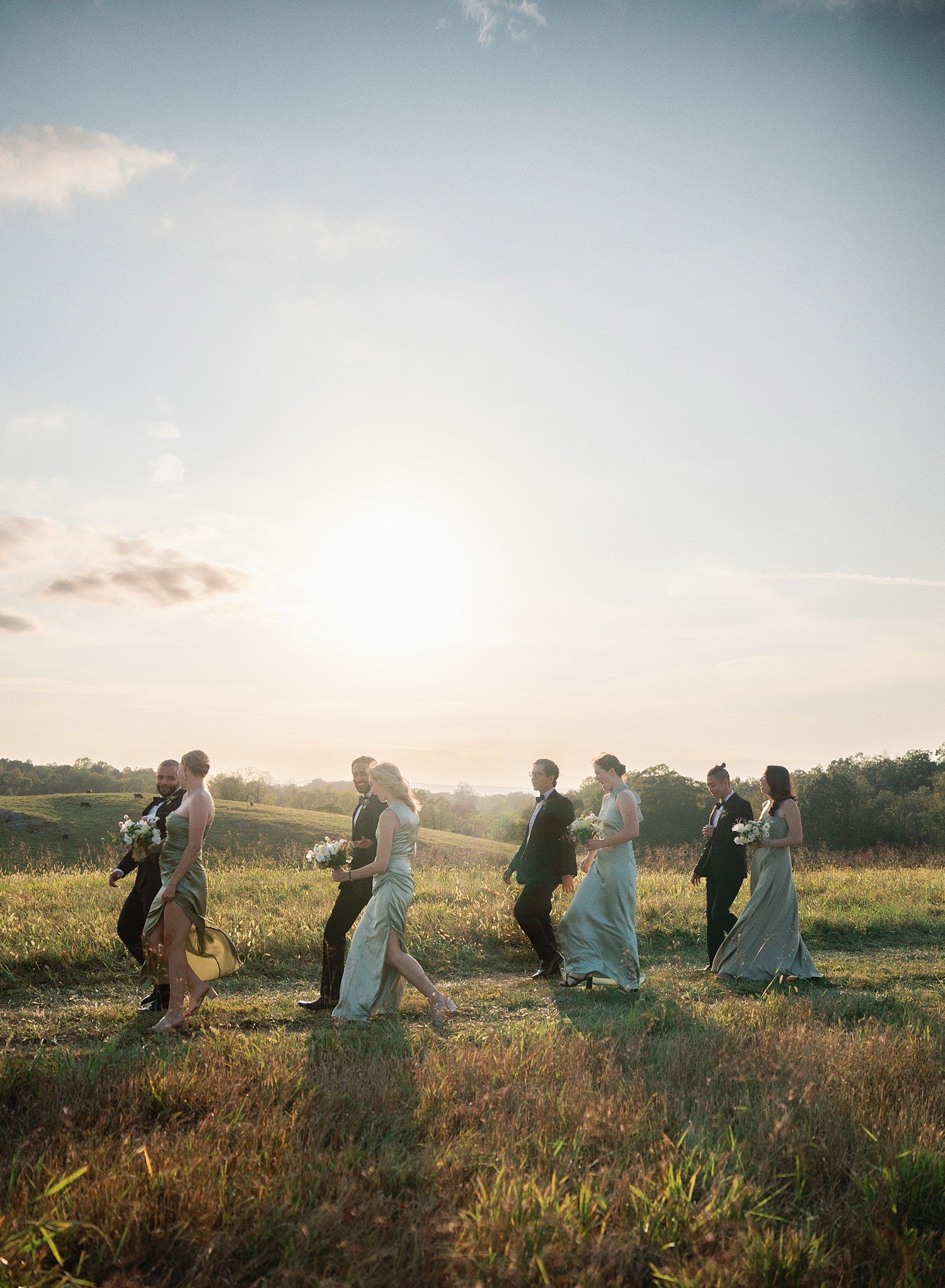 A group of people walking through a golden field at sunset, creating a dreamy silhouette against the warm sky.