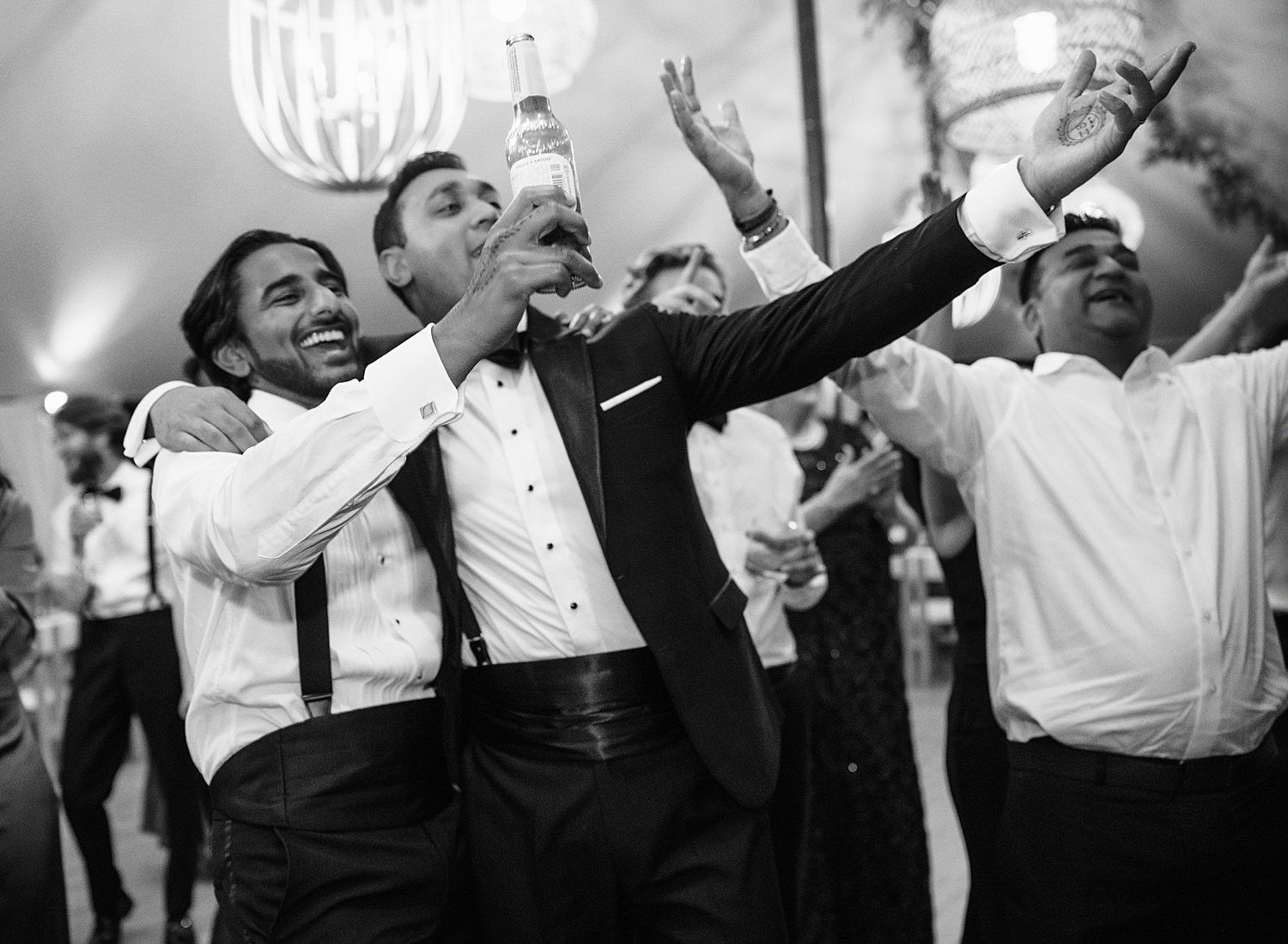 Wedding party dancing and celebrating joyfully on the dance floor at a reception in black and white.