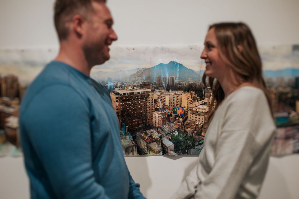 A couple shares a romantic moment while enjoying scenic mountain views from a rooftop observation deck.