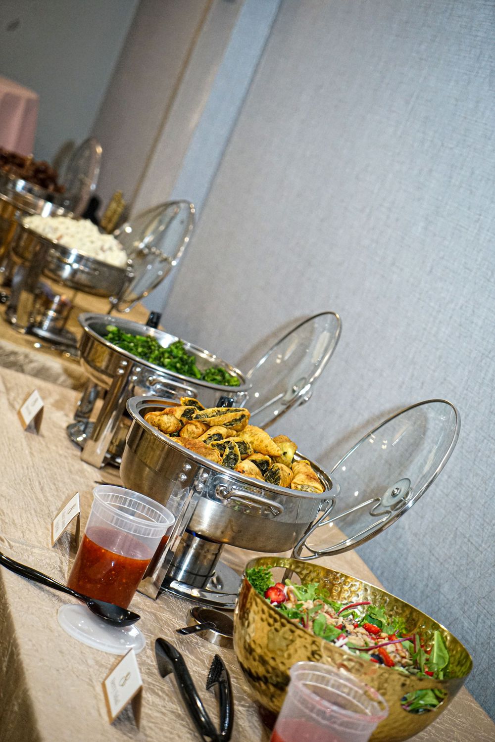 Catering buffet setup with chafing dishes and colorful salads on display.