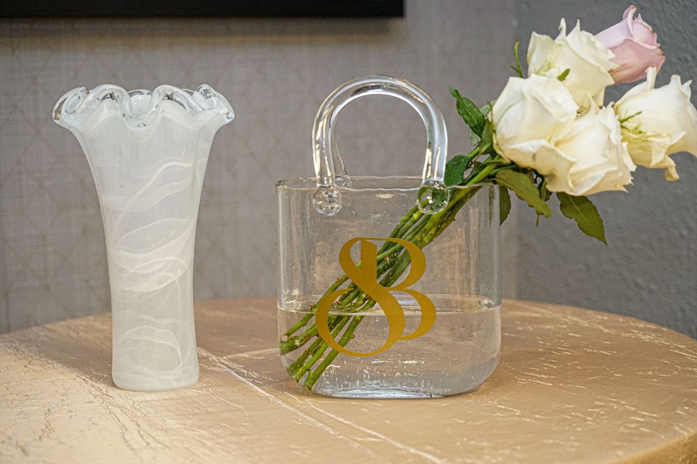 White and pink floral arrangements in glass vases displayed at an event.