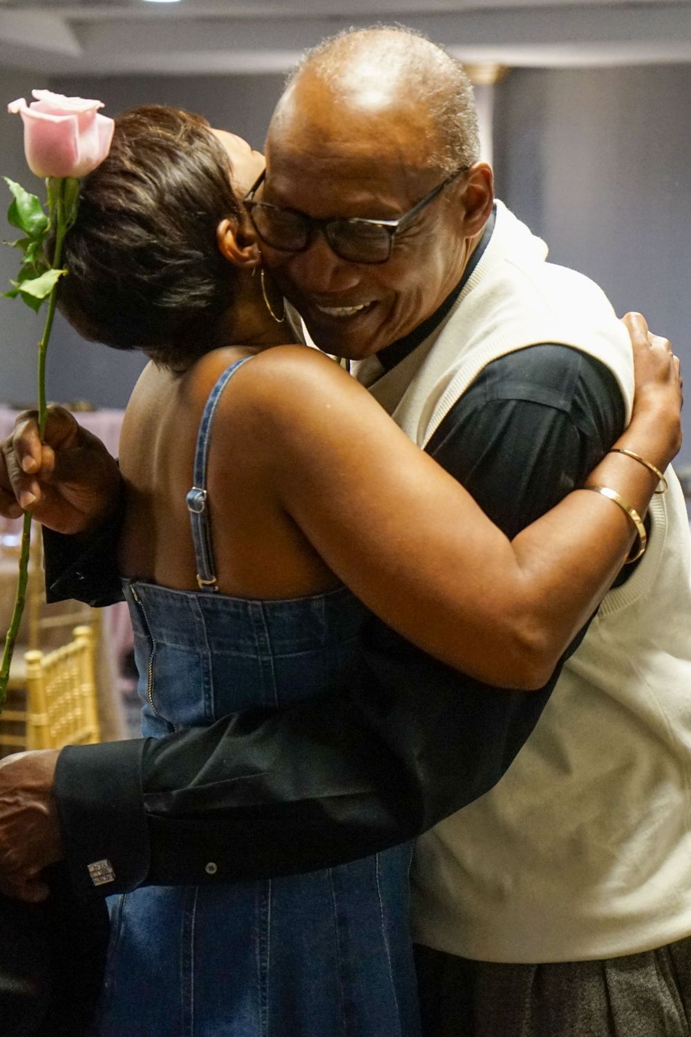 Two people sharing an emotional embrace at an indoor event.