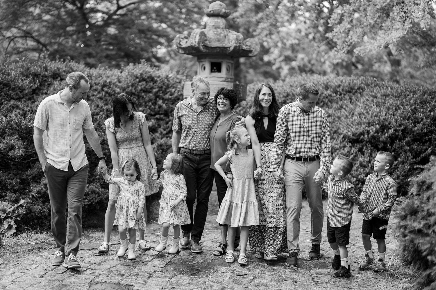 A large extended family group poses together outdoors in coordinated outfits.