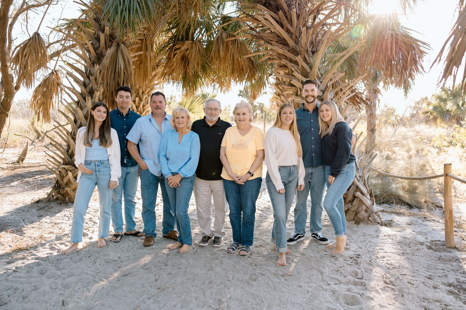 Large family standing together on the beach with palm trees in the background.