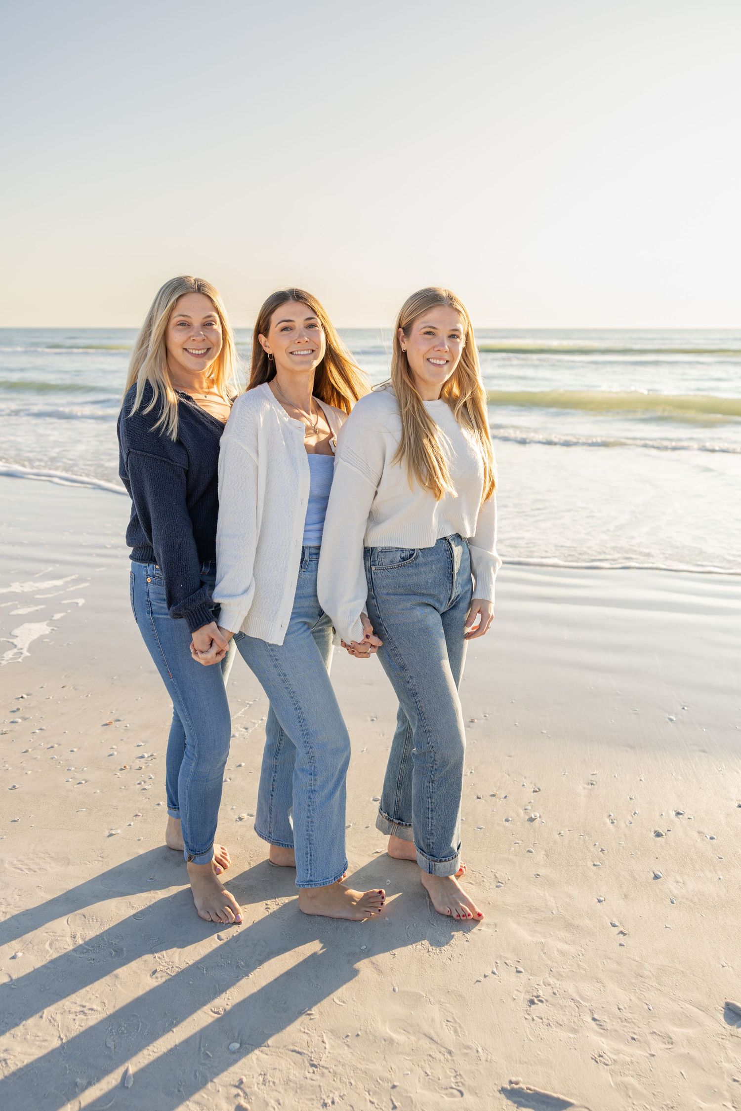 Three sisters standing together on the beach during a lifestyle session.