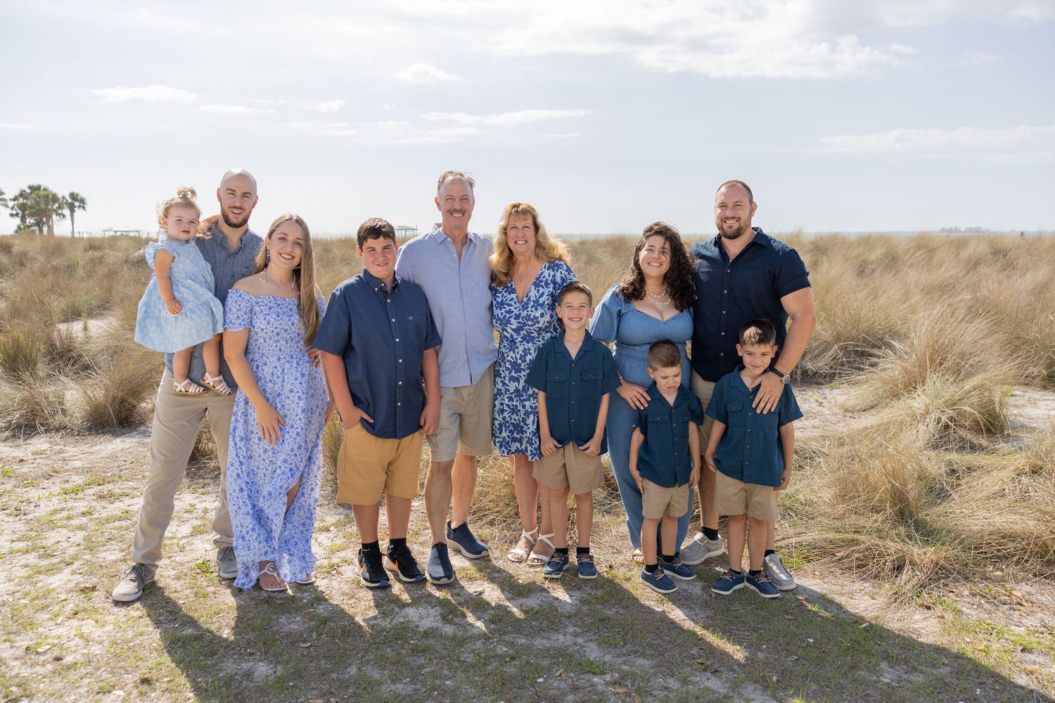 Extended family standing together in a beach dune setting.
