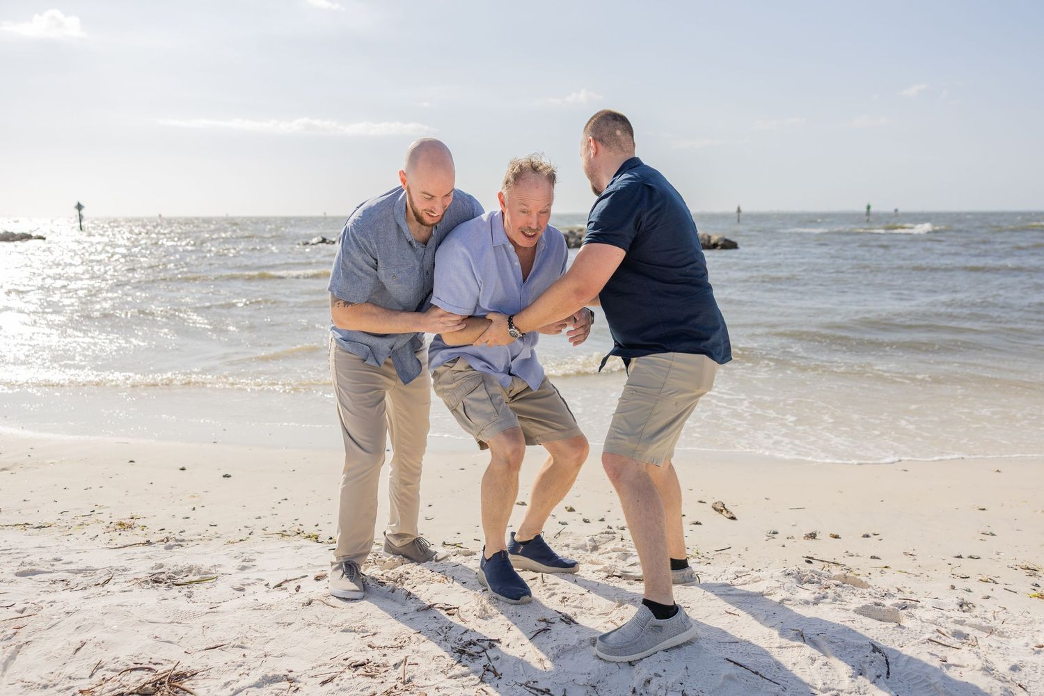 Family laughing together during a playful beach photography session.