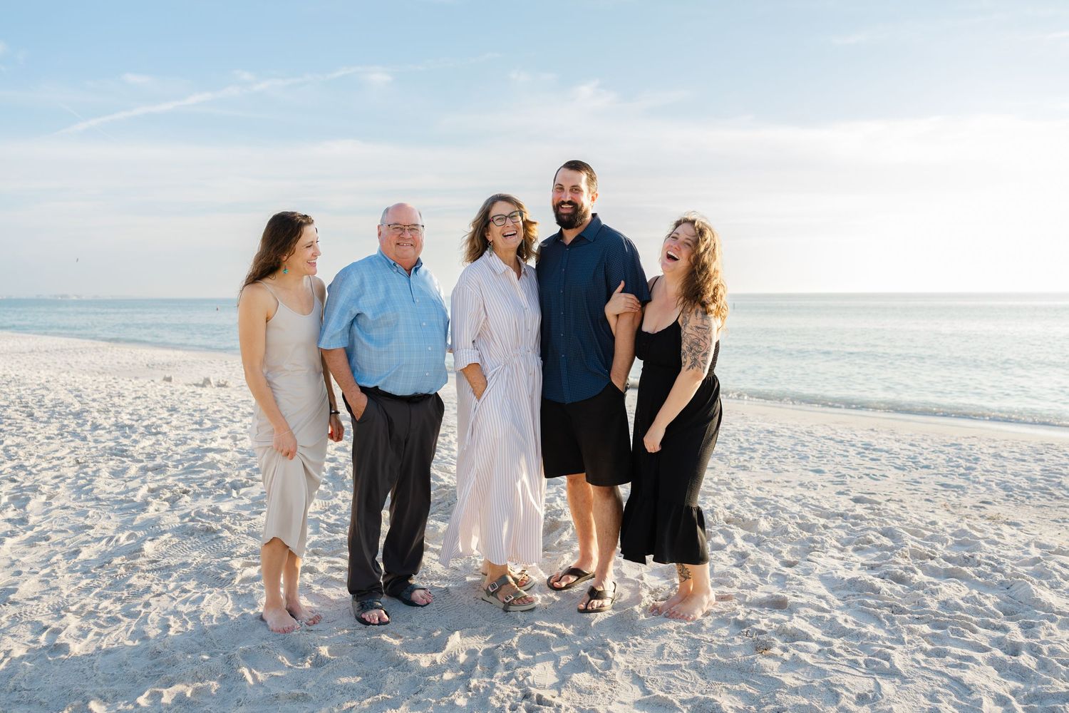 Extended family standing together on a white sand beach.