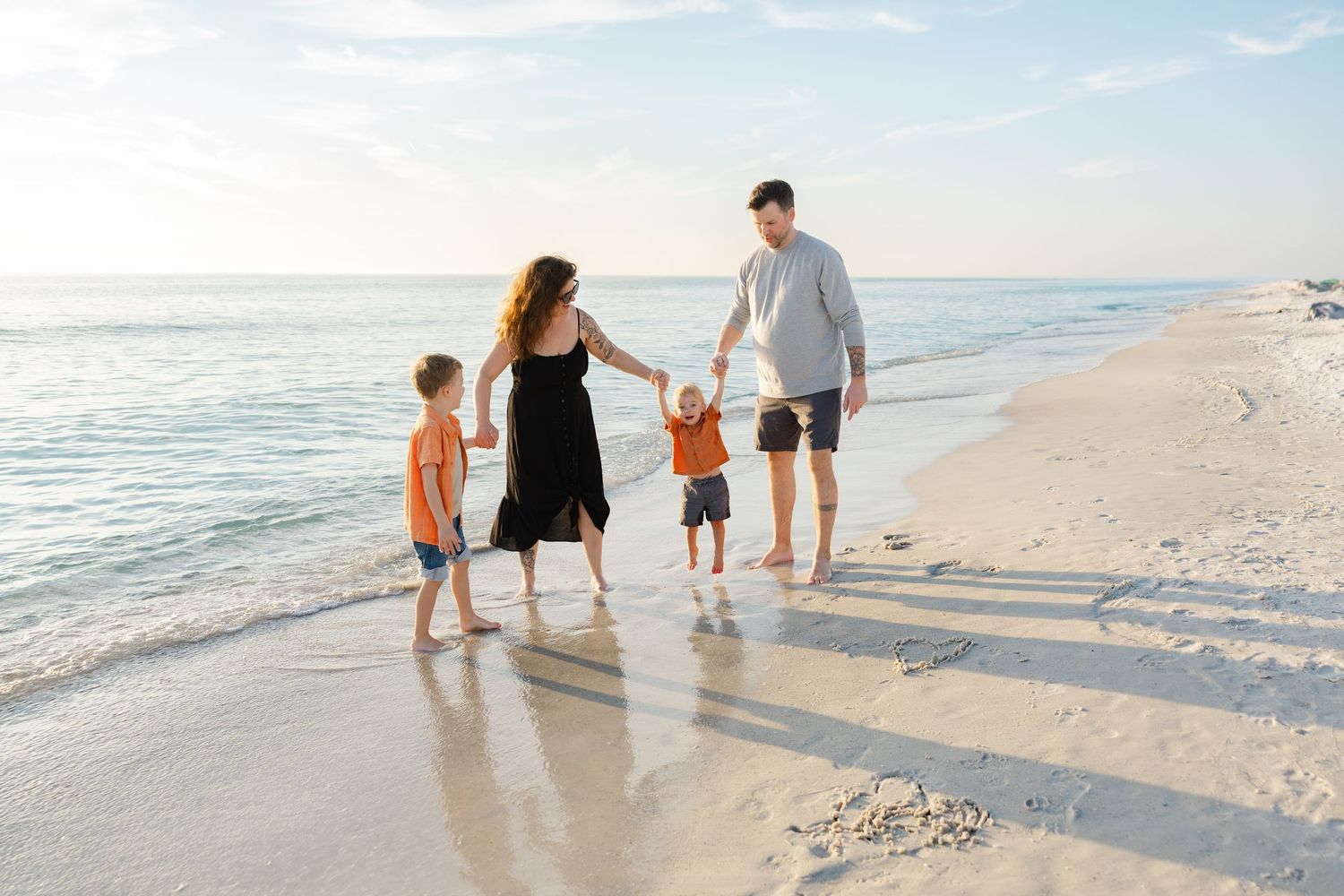 Family walking together along the shoreline during a beach photography session.