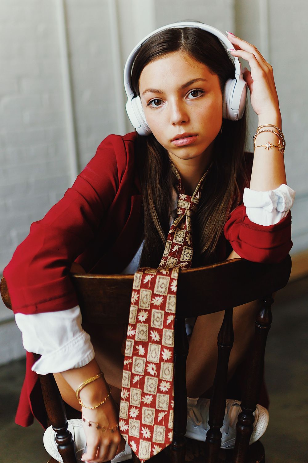 A series of artistic fashion portraits showing a person in a red blazer and patterned tie against a gray backdrop.