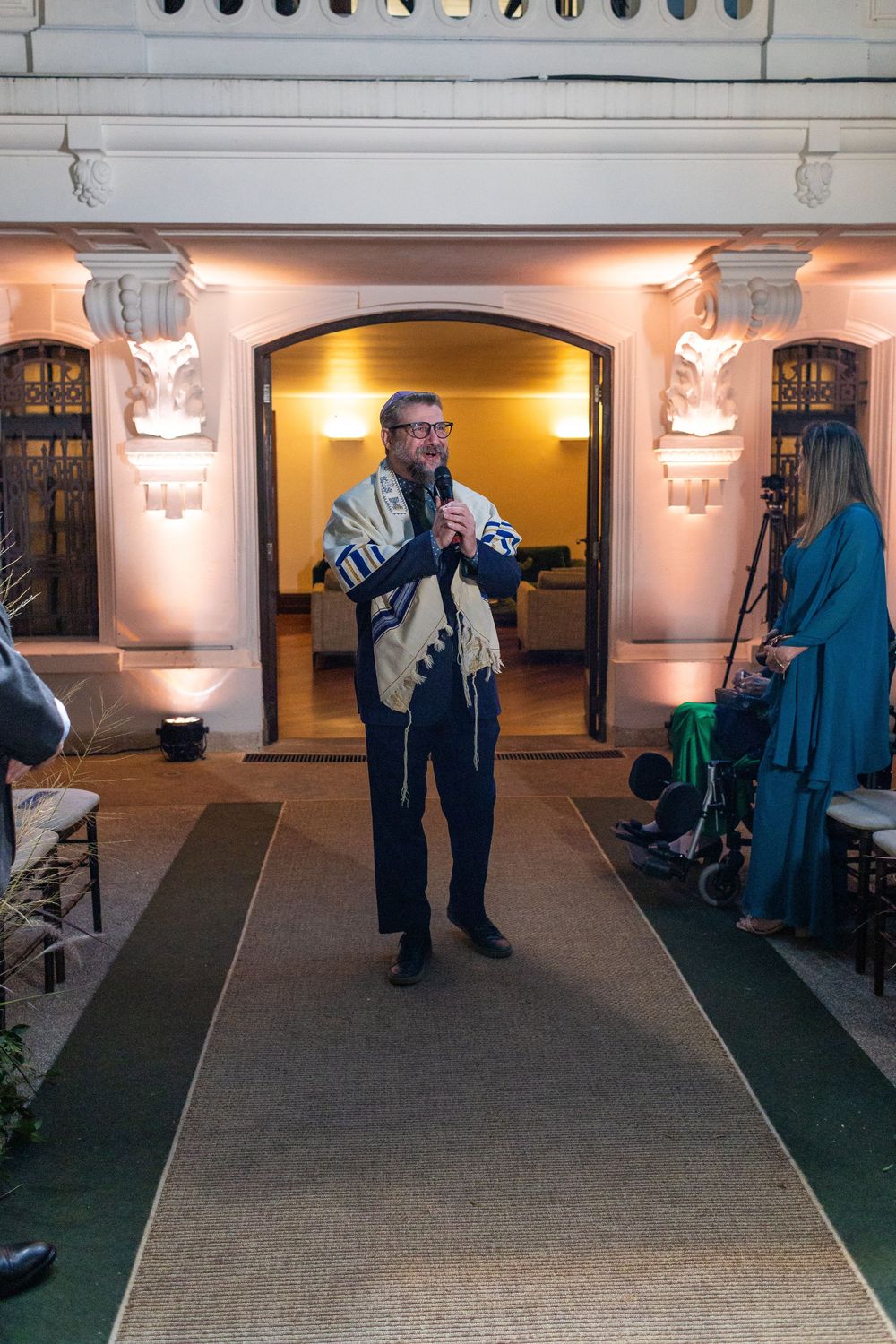 Wedding ceremony taking place in an elegant indoor venue with ornate wall decorations and warm lighting.